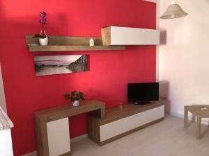 sala de estar con pared roja y TV en Casa Angela, en Vasto