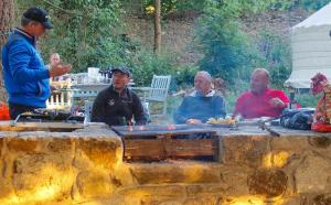 Un gruppo di uomini seduti intorno a un focolare di The Log Cabin @ The Old Forge Glamping a Tullow