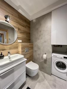 a bathroom with a toilet sink and a washing machine at Apartament 32 Rowery, Spacery w Dolinie Baryczy - 5D Apartamenty in Milicz
