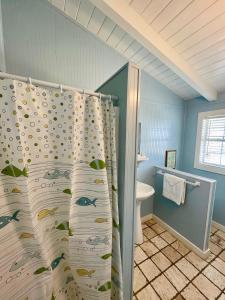 a bathroom with a shower curtain with fish on it at Blue Dolphin Inn and Cottages in Grand Isle