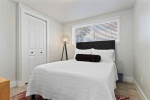 a white bedroom with a large white bed and a window at Amazing New Condo Great Location ! Sugarhouse in South Salt Lake