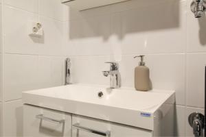 un lavabo blanco con un dispensador de jabón. en City Apartment Tornitupa, en Kuopio
