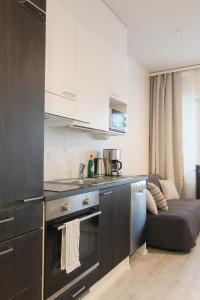 a kitchen with a stove top oven next to a couch at Pramea Apartments Tornitupa in Kuopio