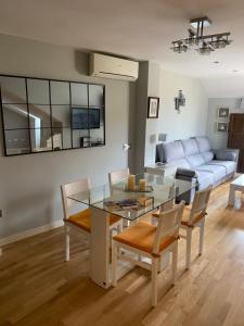 a dining room and living room with a glass table and chairs at VUT Dúplex Miraluz in Cuenca