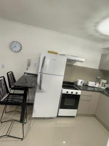 a kitchen with a refrigerator and a table and a clock at Veneto Village in Villa Parque Siquiman