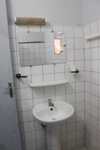 ein weißes Badezimmer mit einem Waschbecken und einem Spiegel in der Unterkunft Ranya in Bobo-Dioulasso