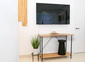 a living room with a table with a television on a wall at Insta Worthy Oasis in Homestead