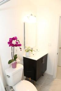 a bathroom with a toilet and a sink with purple flowers at Insta Worthy Oasis in Homestead