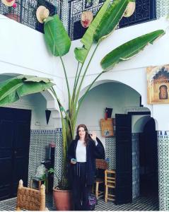 een vrouw die naast een grote plant staat bij Riad Sijane in Marrakesh