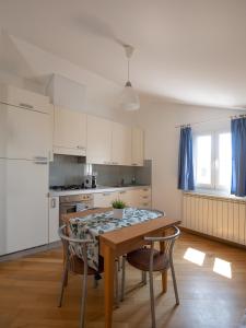 eine Küche mit einem Tisch und Stühlen sowie eine Küche mit weißen Schränken in der Unterkunft Appartamento Pesco "A Casa Felice" in Pietra Ligure
