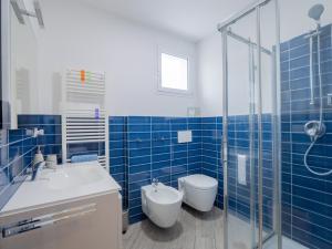 a blue tiled bathroom with a toilet and a sink at Appartamento Melograno "A Casa Felice" in Pietra Ligure