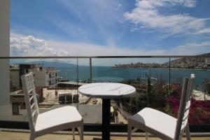 a table and chairs on a balcony with a view of the water at Julia Hotel in Sarandë