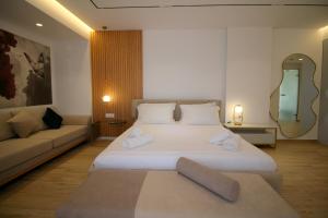 a bedroom with a large white bed and a couch at Julia Hotel in Sarandë
