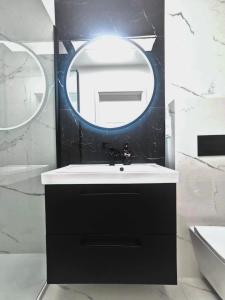 ein Bad mit einem schwarzen Waschbecken und einem Spiegel in der Unterkunft Plażowa Park Apartamenty in Międzywodzie