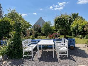 een witte picknicktafel en twee stoelen in een tuin bij ØsterLars blue Pearl in Gudhjem