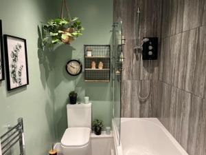 a bathroom with a shower and a toilet and a clock at Stunning Bright Two Bedroom Apartment In Southbourne in Southbourne