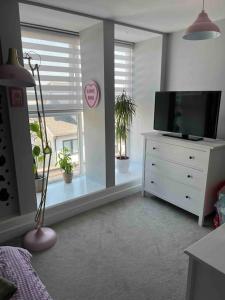 a bedroom with a dresser with a television and a window at Stunning Bright Two Bedroom Apartment In Southbourne in Southbourne