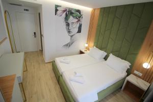a bedroom with a bed with a painting on the wall at Julia Hotel in Sarandë