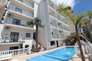 an apartment building with a swimming pool and palm trees at Julia Hotel in Sarandë