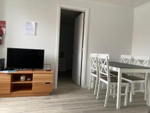 a dining room with a table and chairs and a television at Casa do Girassol in Horta