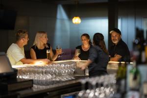 a group of people sitting at a bar with wine glasses at Millennium Hotel Rotorua in Rotorua