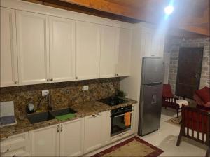 a kitchen with white cabinets and a stainless steel refrigerator at Villa delux in Qeparo
