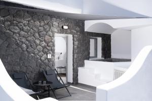 Habitación con pared de piedra, 2 sillas y mesa. en Griseo Villas, en Karterados