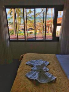 a bed with a towel on it in a room with windows at Enseada dos Mares Beach Bungalows in São Miguel do Gostoso