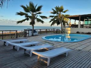 una piscina con 2 tumbonas junto a la playa en Enseada dos Mares Beach Bungalows en São Miguel do Gostoso