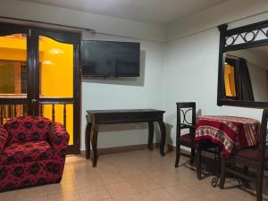 THIZMA HOTELES Ex HotelSantaMaria في اياكوتشو: غرفة معيشة مع طاولة وكرسي وتلفزيون