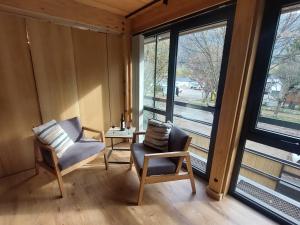 a room with two chairs and a table and windows at Departamento muy cálido y luminoso, excelente ubicación en el centro de SMA. 9V5 in San Martín de los Andes
