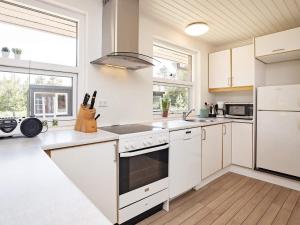 a white kitchen with white appliances and windows at 6 person holiday home in Bl vand in Ho