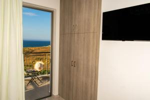Una habitación con televisión y un balcón con vista al mar. en Akontio Apartment with Sea View, en Panormos Rethymno