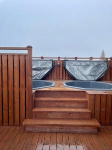 2 bañeras de hidromasaje en una terraza de madera con escaleras en Lovely apartment with hot tub access, en Akureyri