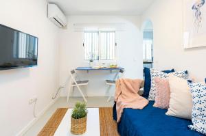 ein Wohnzimmer mit einem blauen Sofa und einem Schreibtisch in der Unterkunft Apartamento de un dormitorio cerca de la playa in Estepona