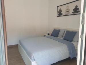 a white bedroom with a bed with blue pillows at Seafront Apartment Strunjan in Strunjan