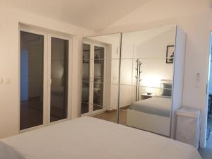 a white bedroom with a bed and a mirror at Seafront Apartment Strunjan in Strunjan