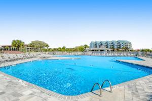 a large swimming pool with chairs and blue water at Hilton Head Beach & Tennis Unit B222 in Hilton Head Island