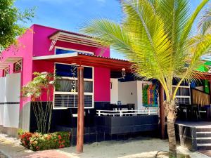 een roze huis met een palmboom ervoor bij Hotel Casa Playa Zorritos in Zorritos