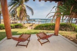 two chairs sitting on a porch looking at the beach at Casa Don Luis Lujosa casa frente a la playa 