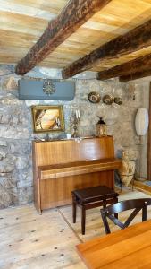 un pianoforte in legno in una stanza con un muro in pietra di Rustic house Pojata a Njeguši