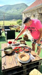 un uomo che prepara il cibo su un tavolo da picnic di Rustic house Pojata a Njeguši