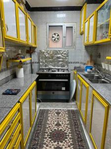 a kitchen with yellow cabinets and a stove top oven at Spacious flat 7 mins to Airport in Cairo