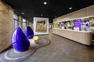 een lobby met paarse stoelen en een winkel bij prizeotel Erfurt-City in Erfurt