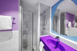 La salle de bains est pourvue d'un lavabo violet et d'un miroir. dans l'établissement prizeotel Erfurt-City, à Erfurt