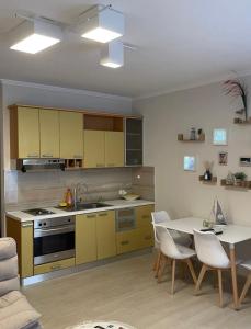 a kitchen with yellow cabinets and a table with chairs at Aquamarine Dreams Apartments in Beach of Durres 150 m from Sea in Durrës