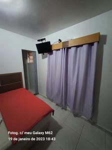 サンパウロにあるHotel Pousada Clínicas Valenteのカーテンと赤いベンチとテレビのある部屋