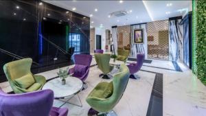 eine Lobby mit lila und grünen Stühlen und einem Tisch in der Unterkunft Hotel Business Bay das ehemalige Staycation Hotel in Sindelfingen
