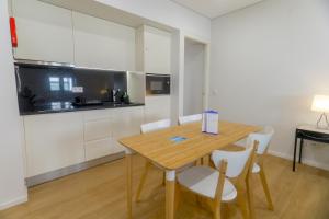 una cucina con tavolo in legno e armadietti bianchi di Porto Downtown Living - Picaria Apartments a Porto