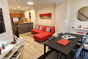 ein Wohnzimmer mit einem Tisch und einem roten Sofa in der Unterkunft Location and Lifestyle - 1 bed, 2 bath + parking in Sydney